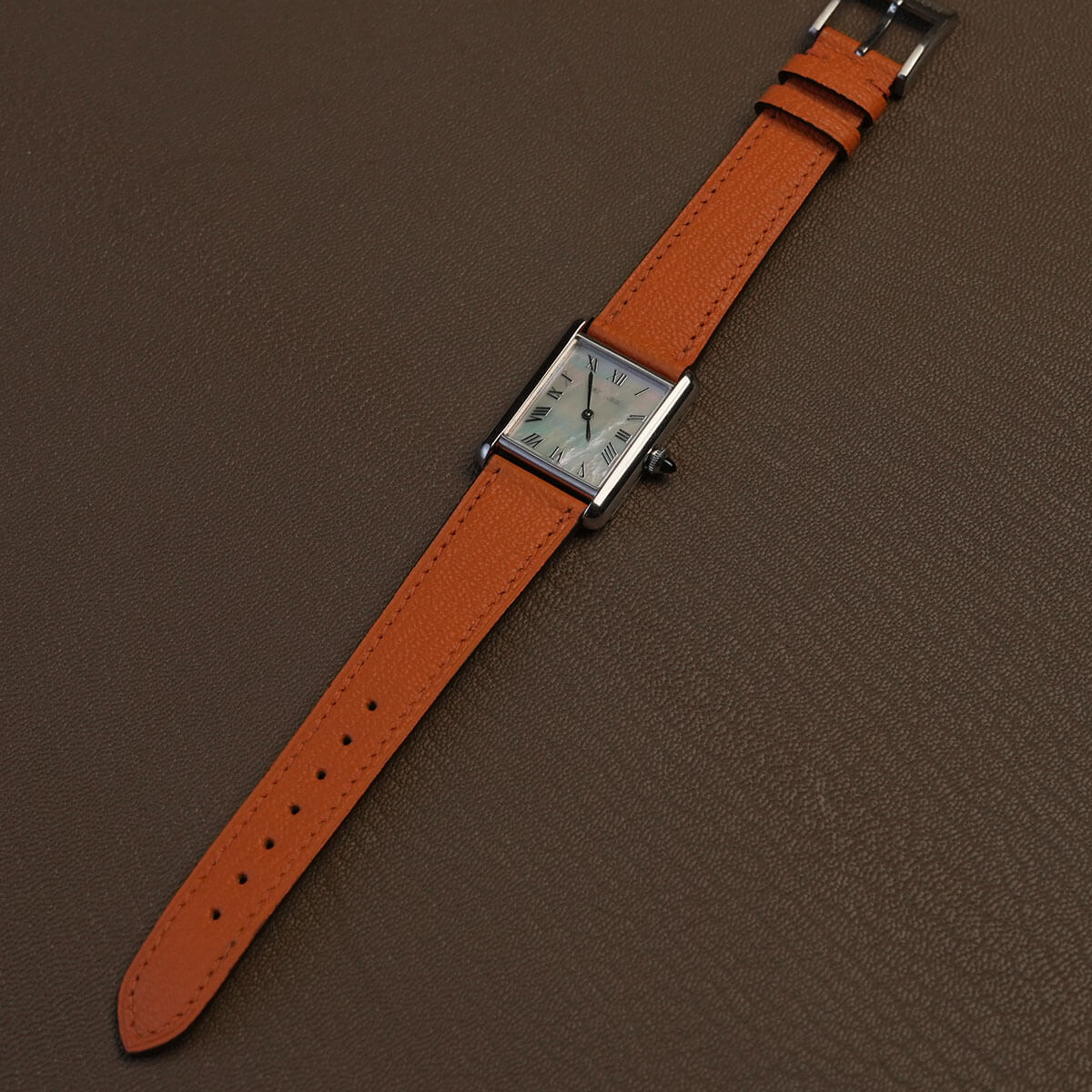 Complete Orange Alran goatskin watch band mounted on luxury tank watch on leather background