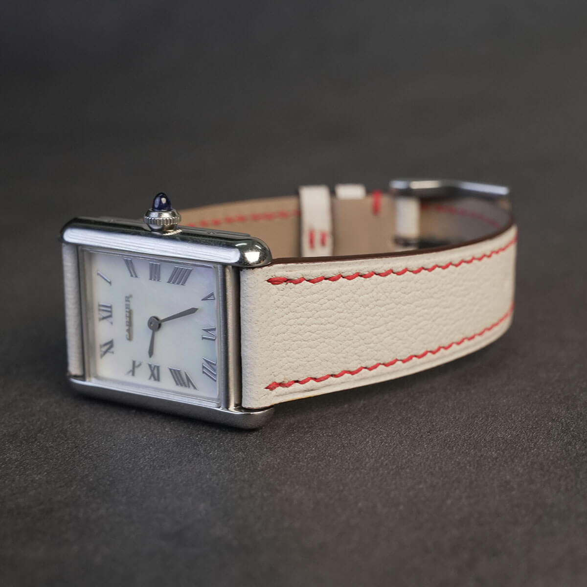 Side profile of slim 1.8mm Beige White leather watch strap with red stitching on tank watch case