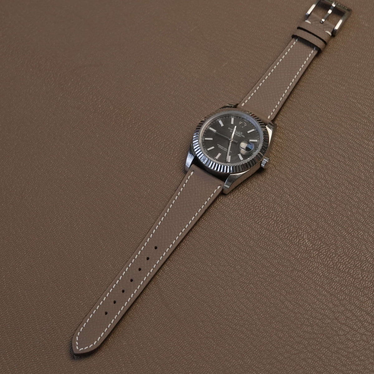 Complete Etoupe French Epsom calfskin watch strap on stainless steel luxury watch over leather desk pad