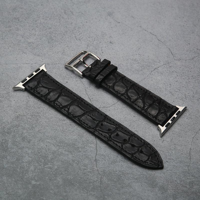 Black aligator leather watch strap with silver buckle on a gray surface