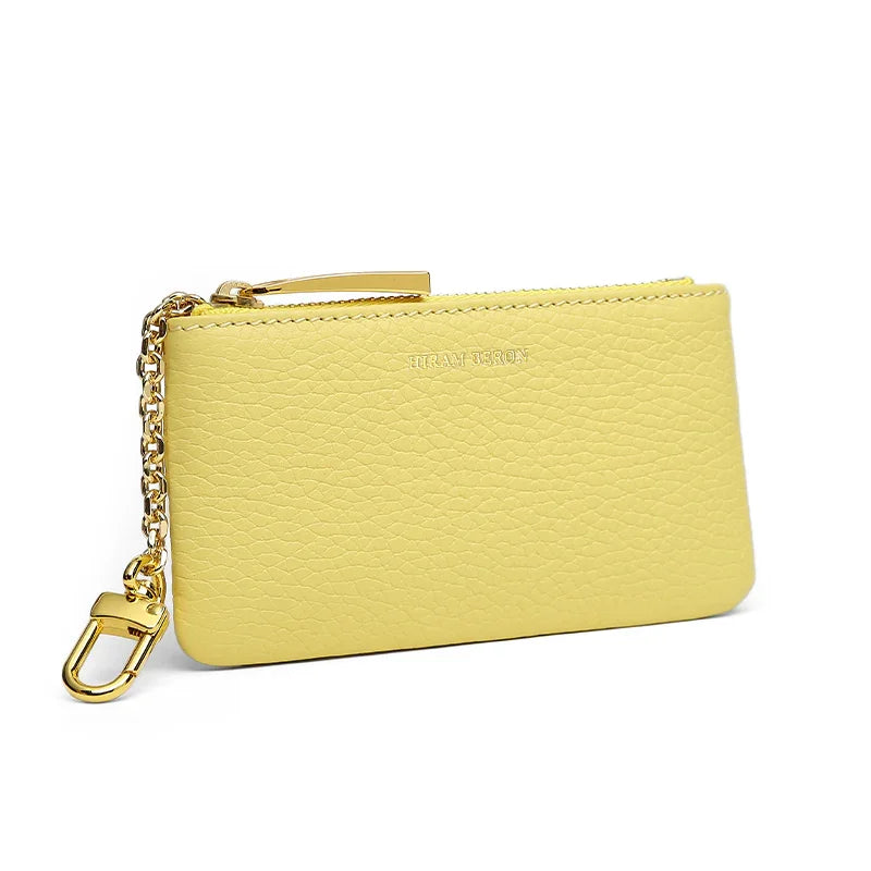 Yellow pebble leather key case with a chain detail on a white background