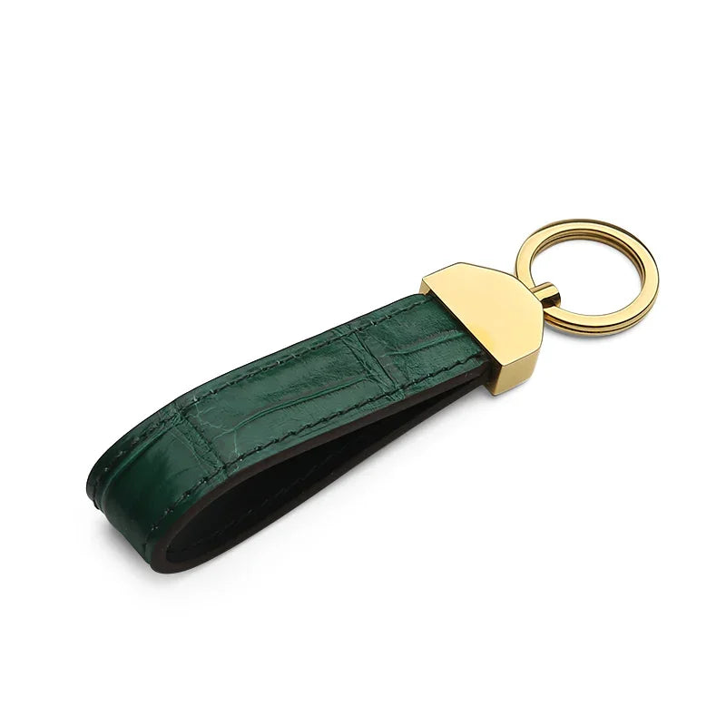 Green crocodile skin keychain with gold accent on a white background