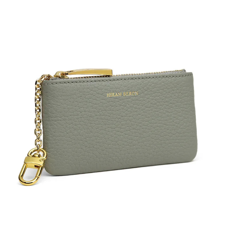 grey pebble leather key case with gold chain and clasp on a white background