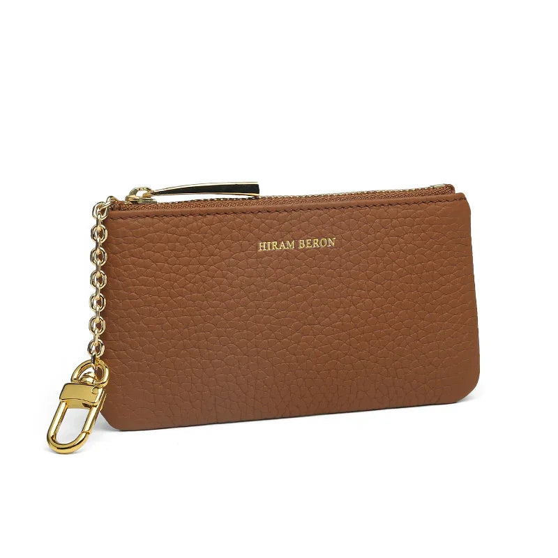 Brown leather key case with gold chain and clasp on a white background
