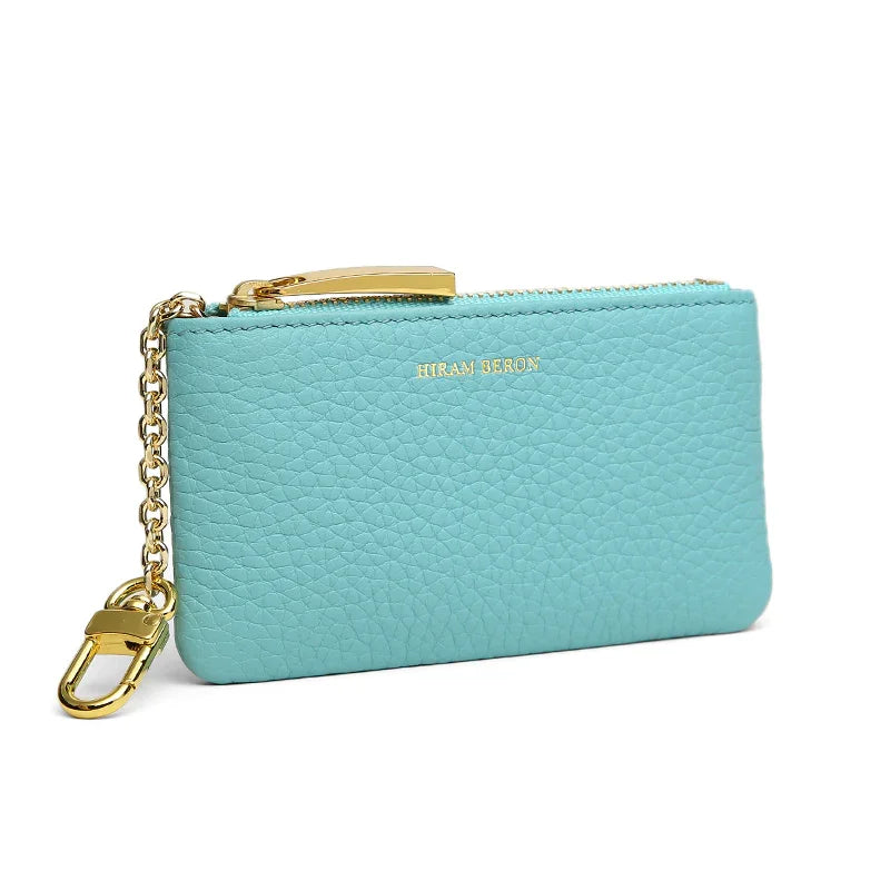 Turquoise leather key case with gold chain and clasp on a white background