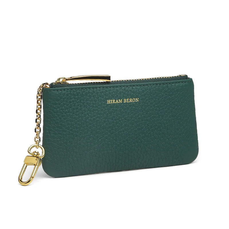 Green leather key case with gold zipper and chain on a white background