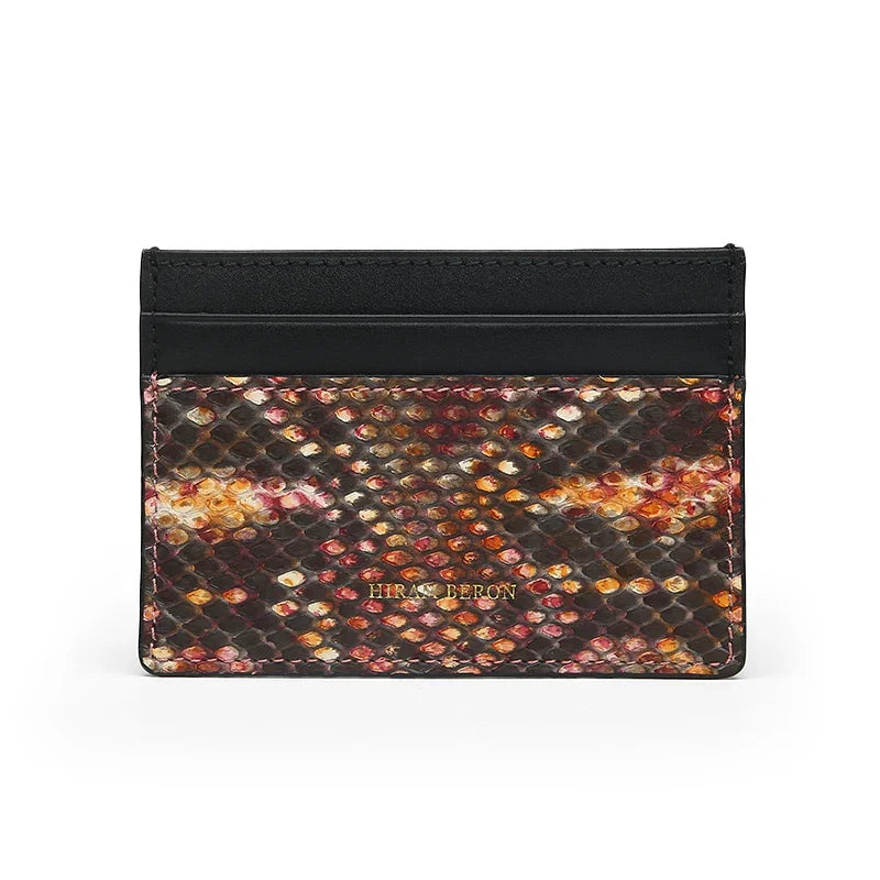 Multicolored real snake skin cardholder with black leather trim on a white background