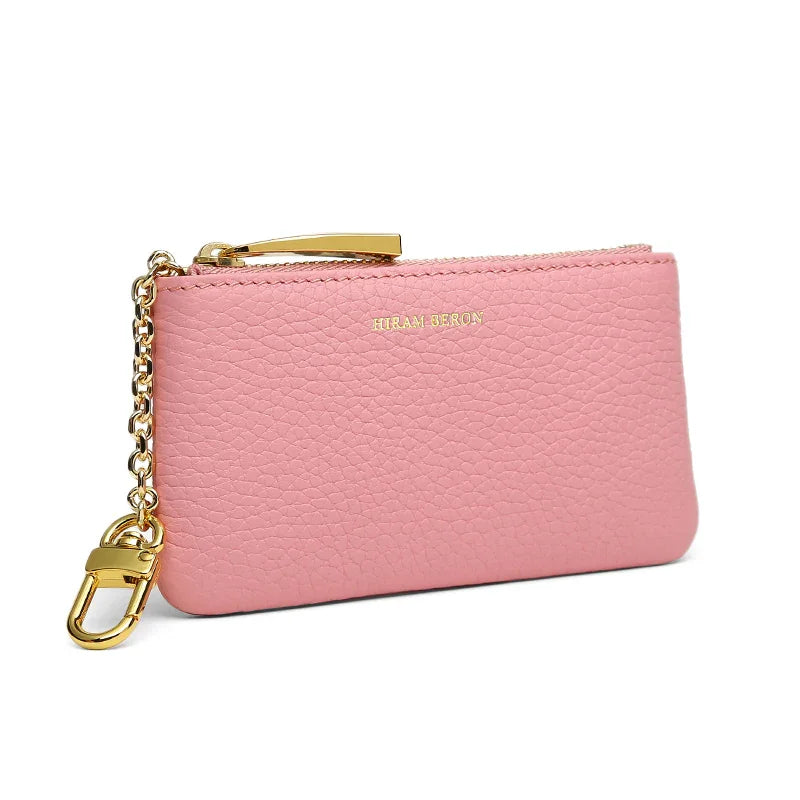 Pink pebble leather key case with gold chain and clasp on a white background