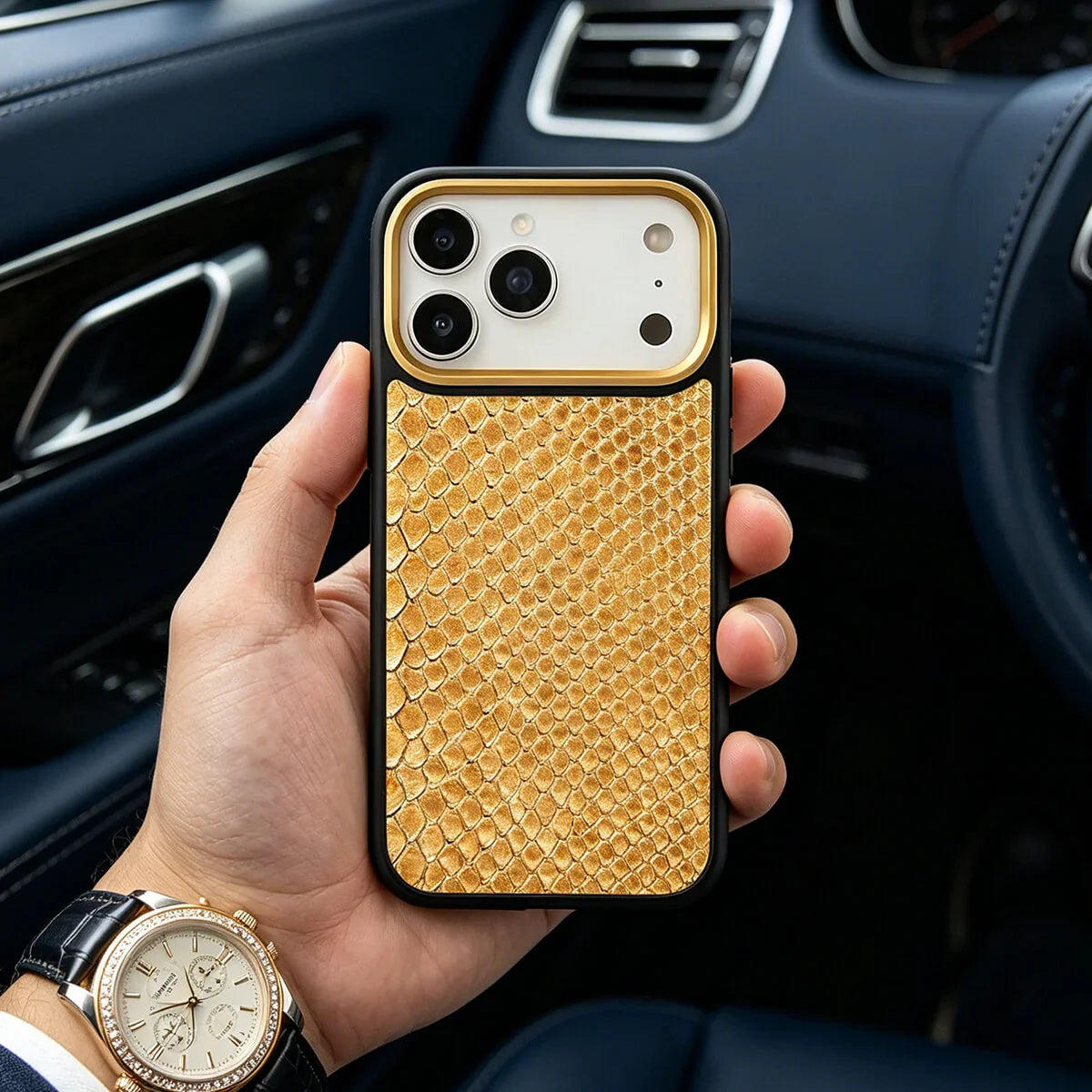 Hand holding an iphone 17 pro with a gold snake skin pattern case inside a car.