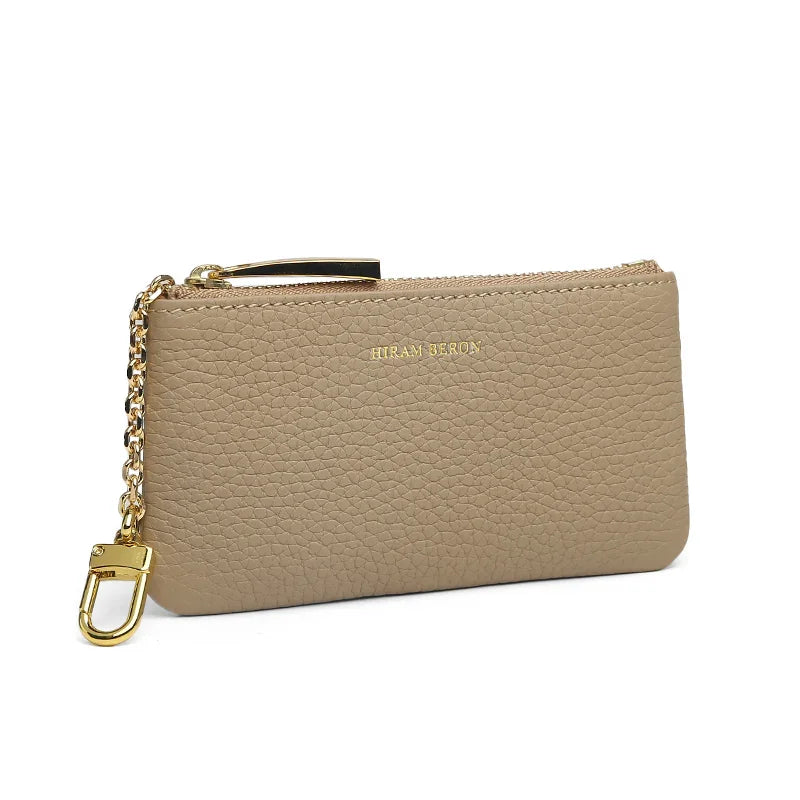 Beige leather key case with gold chain and clasp on a white background