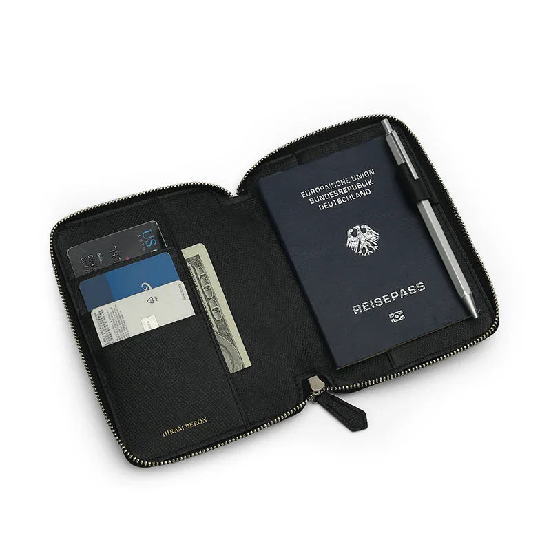 Black leather passport wallet with a passport, card, and money on a white background