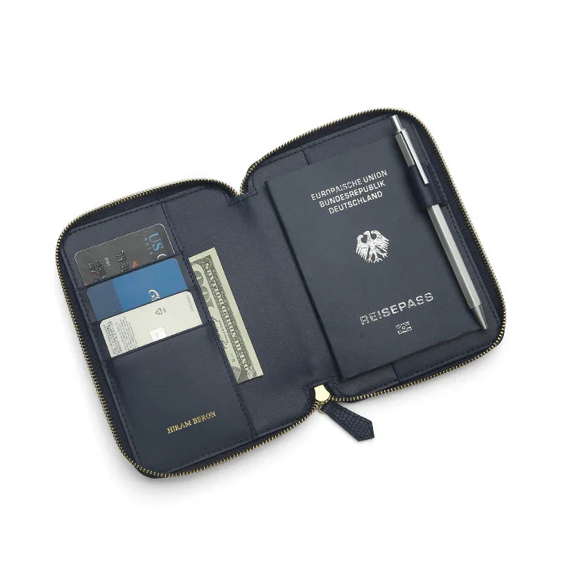 Navy blue leather passport wallet with a German passport, cards, and a pen on a white background
