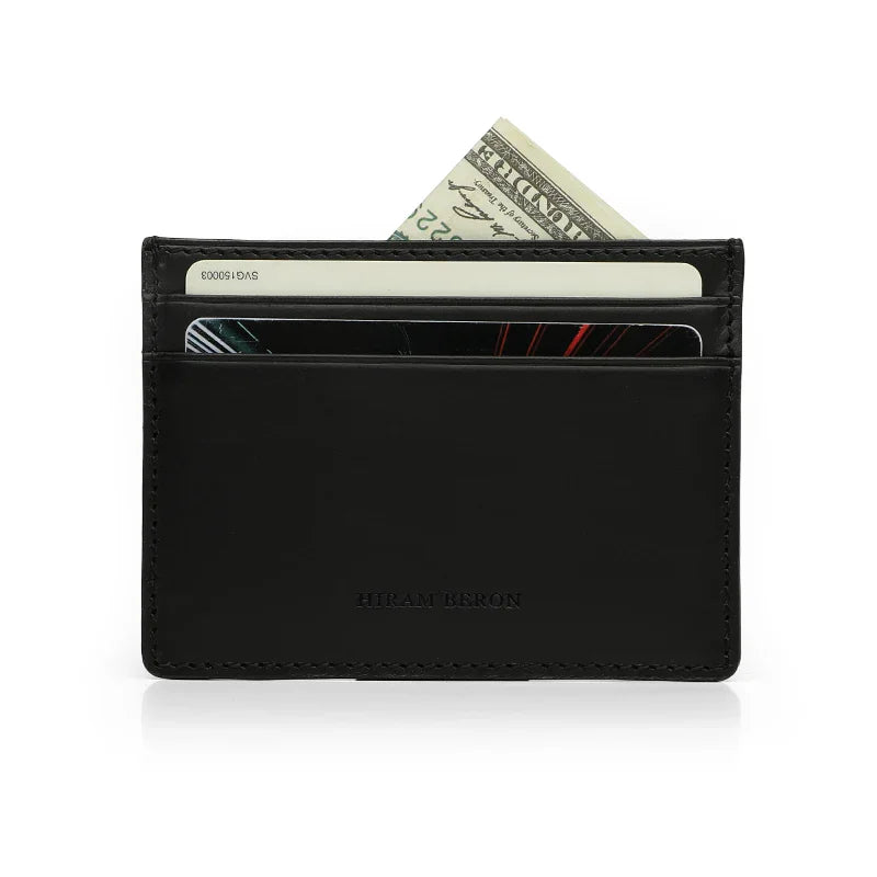 Black vegetable tanned leather card case with money and cards on a white background