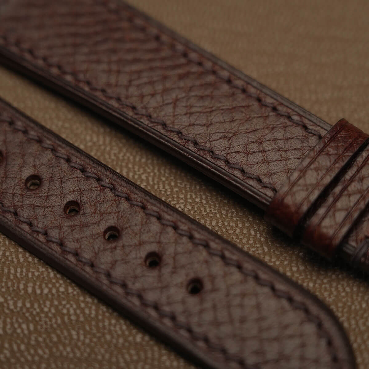 Macro texture of Italian Badalassi embossed veg-tan leather showing precision stitching and sealed edge finish