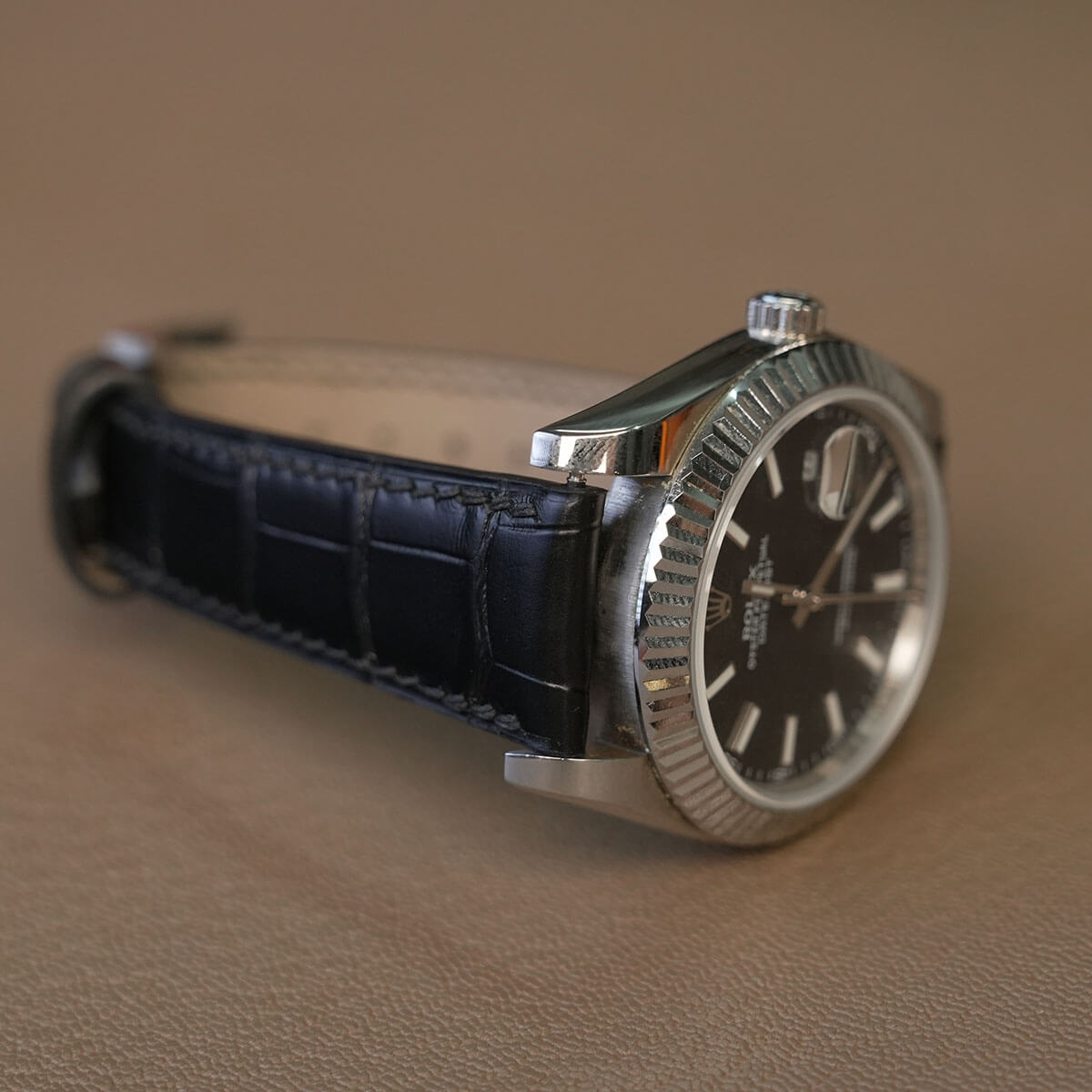 Side profile demonstrating thick padded lug tapering to thin buckle end on black alligator watch strap