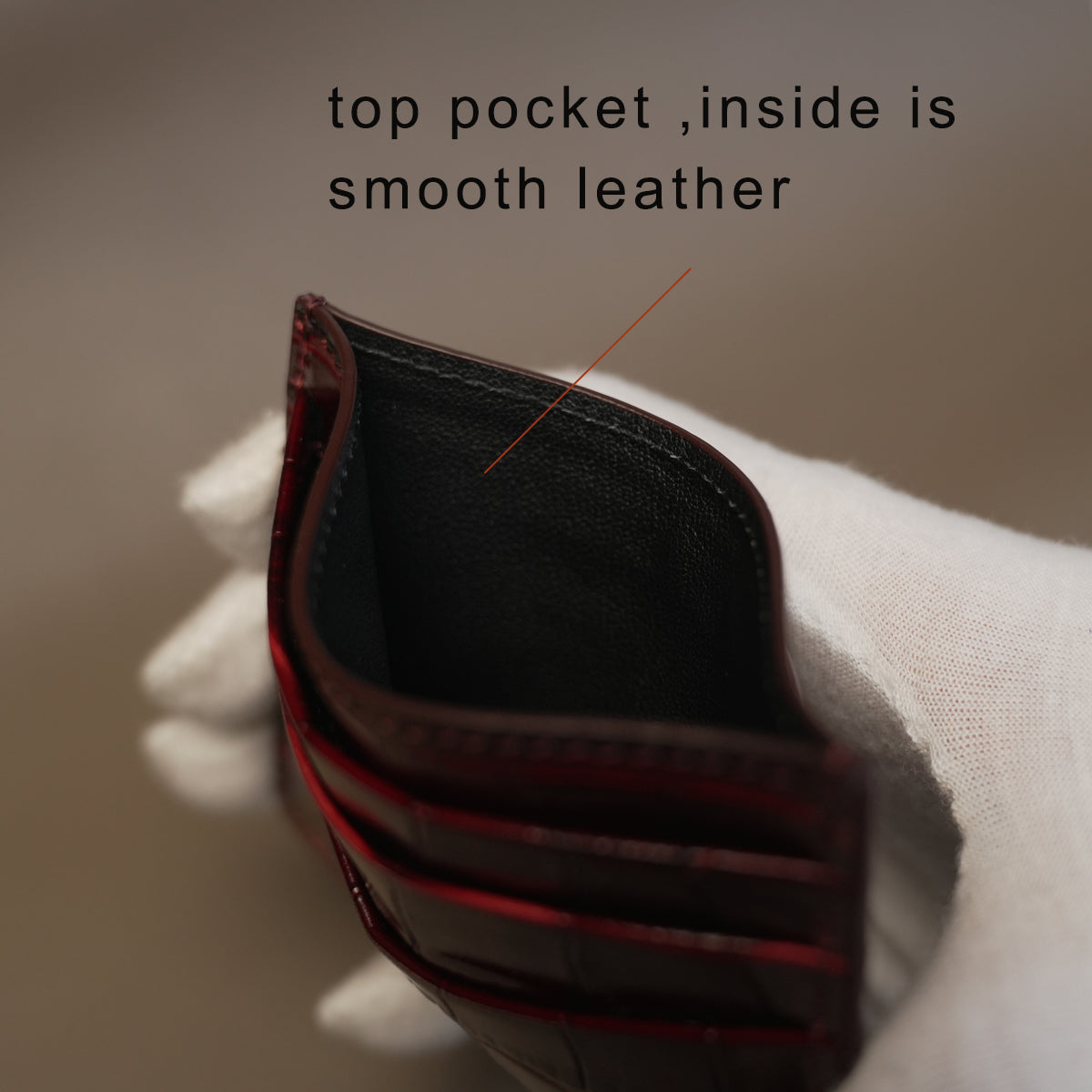 Close-up of a leather card holder with text indicating the top pocket is smooth.
