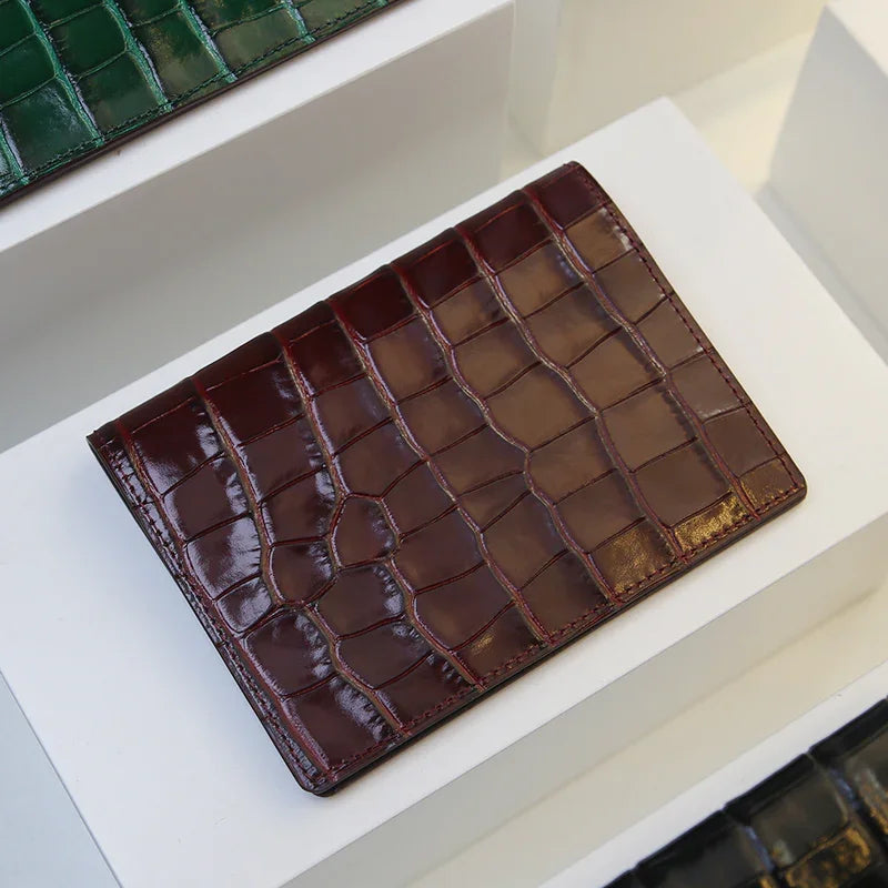 Burgundy crocodile-patterned leather passport wallet on a white surface