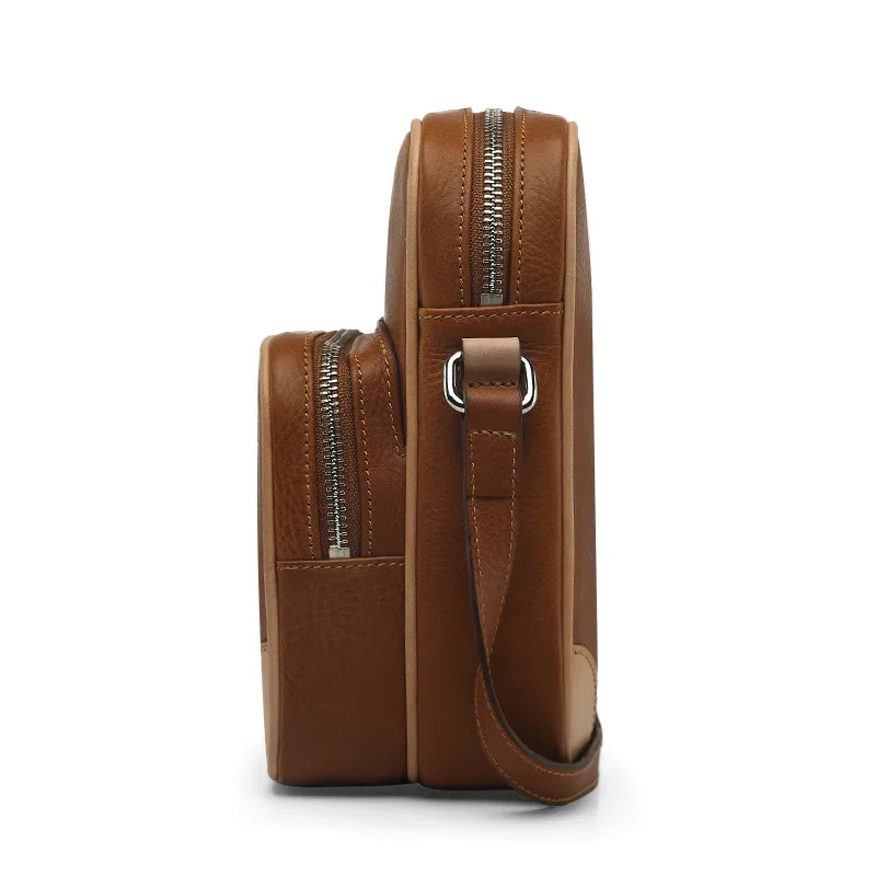 Brown leather crossbody bag with zippers on a white background