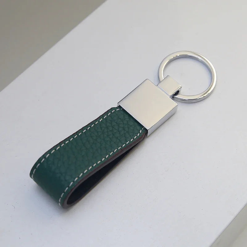 Green leather key fob with silver keyring on a light gray surface