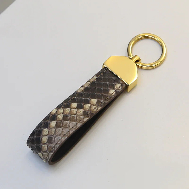 Keychain with snake skin pattern and gold accent on a light gray background
