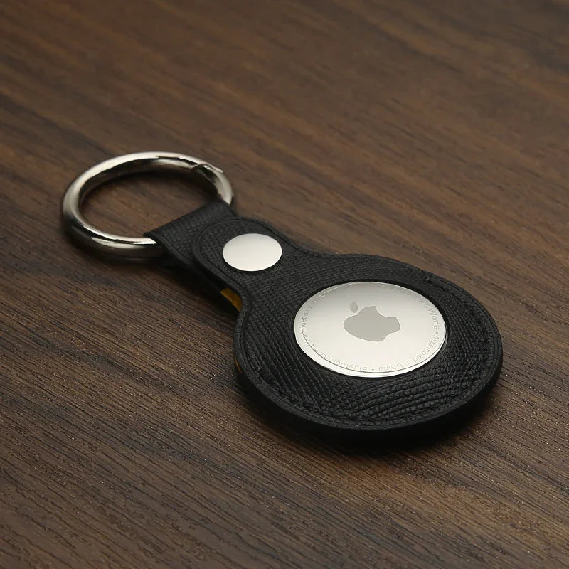 Black leather saffiano keychain with a metallic Apple logo on a wooden surface