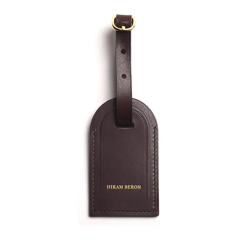 coffee brown leather luggage tag with a gold buckle on a white background