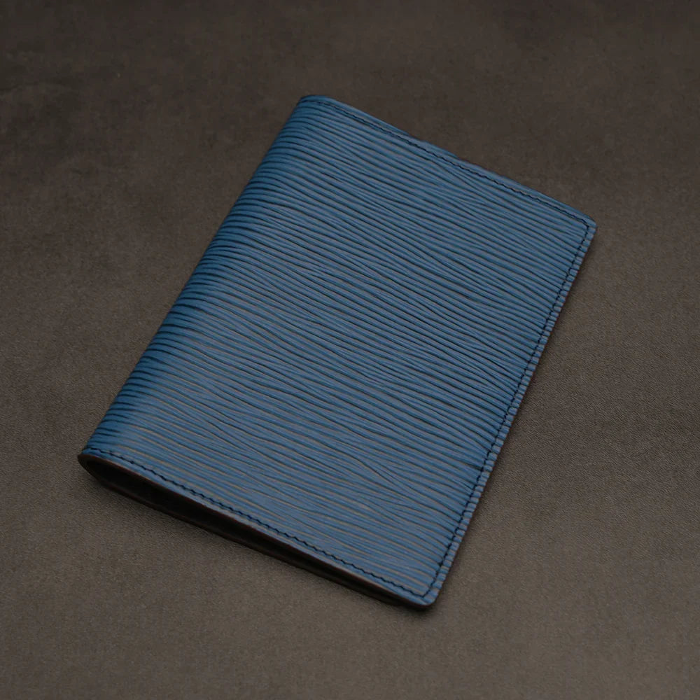 Blue leather passport holder on a dark grey background