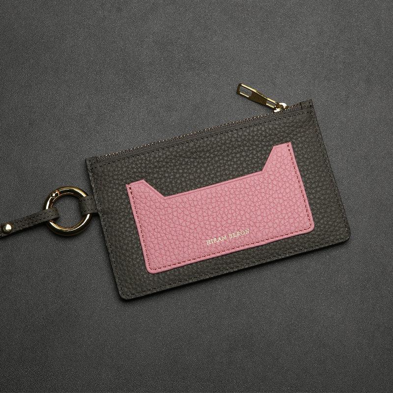 etoupe and pink leather cardholder with gold ring on a dark gray background