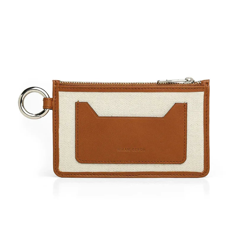 Small card holder with brown leather pocket and beige fabric surface on a white background