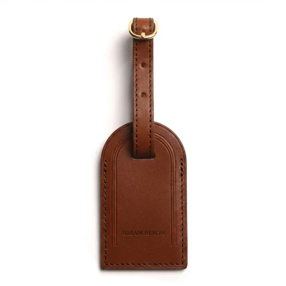 Brown leather luggage tag with gold accent on a white background