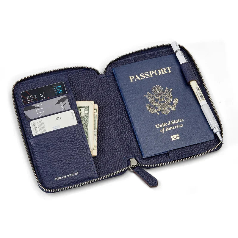 Navy blue pebble leather passport wallet with passport, cards, and money on a white background