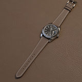 Complete Etoupe French Epsom calfskin watch strap on stainless steel luxury watch over leather desk pad