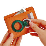 Orange leather wallet with green ring holder, holding cash and cards, ideal for minimalist everyday carry.