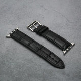 Black aligator leather watch strap with silver buckle on a gray concrete surface
