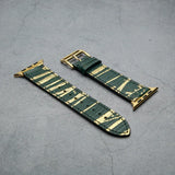 Green and gold lizard skin watch strap on a gray surface