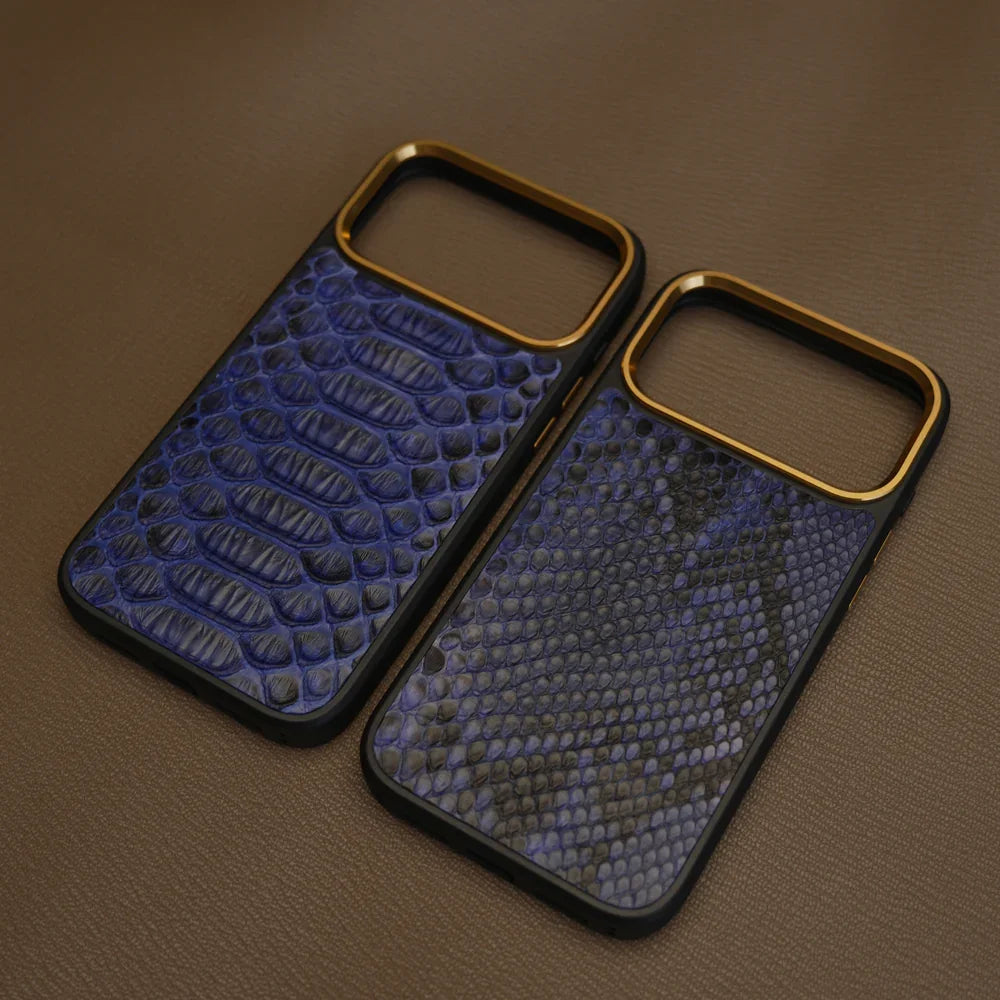 Two blue python skin phone cases with gold edges on a brown surface