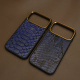 Two blue python skin phone cases with gold edges on a brown surface