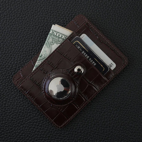 Brown crocodile pattern leather card holder with money and cards on a dark textured surface