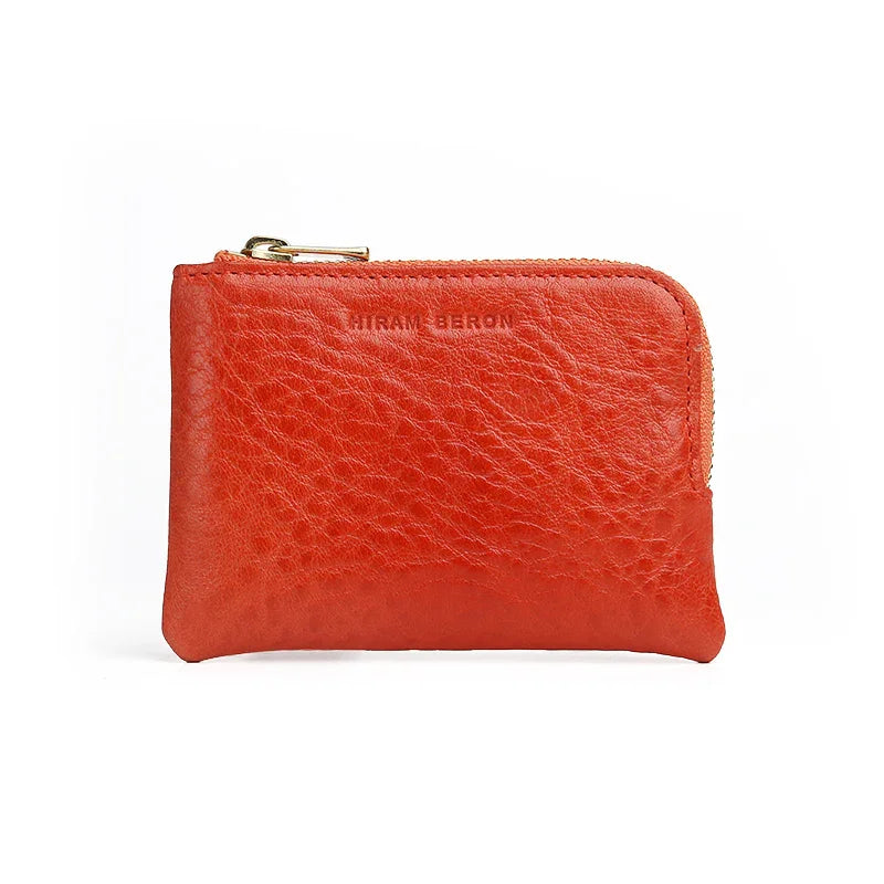 Red leather coin case with gold zipper on a white background