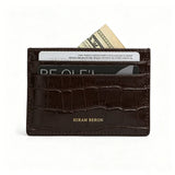 Brown aligator patterned wallet with cards and money on a white background