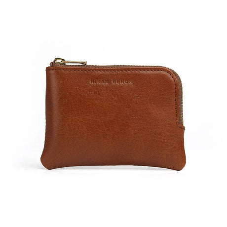Brown vegetable tanned leather coin pouch with gold zipper on a white background