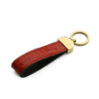 Red crocodile skin keychain with gold accent on a white background