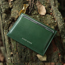 Green leather card wallet with 'Hiram Beron' branding on a textured surface