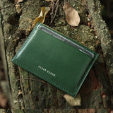 Green leather card wallet with 'Hiram Beron' branding on a textured surface