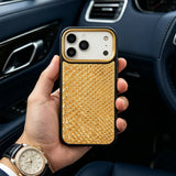 Hand holding an iphone 17 pro with a gold snake skin pattern case inside a car.