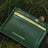 Green vegetable tanned leather wallet with 'Hiram Beron' branding on a natural background