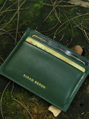 Green vegetable tanned leather wallet with 'Hiram Beron' branding on a natural background