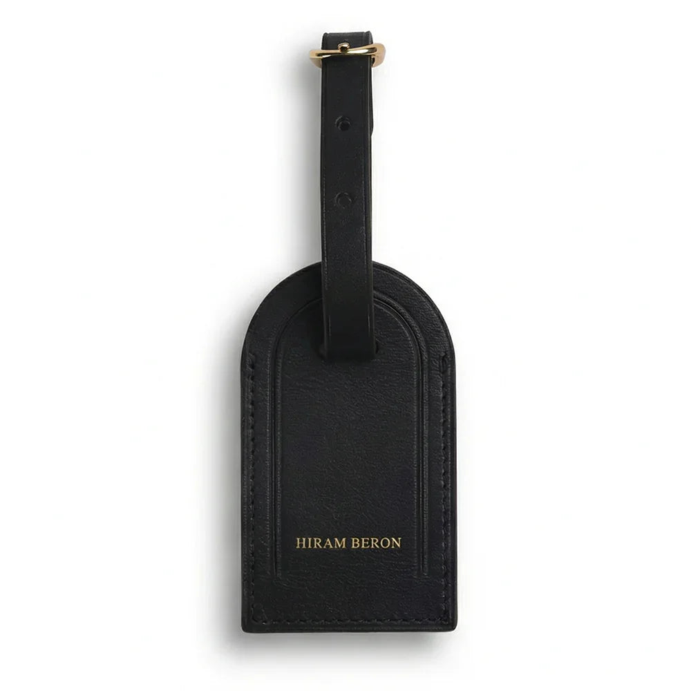 Black leather luggage tag with 'Hiram Beron' branding on a white background