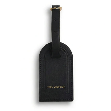 Black leather luggage tag with 'Hiram Beron' branding on a white background