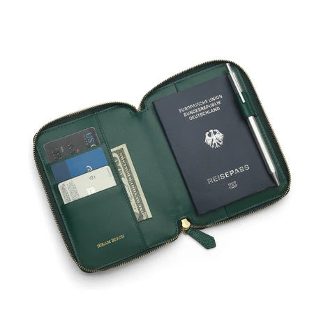 Green leather passport wallet with passport, cards, and pen on a white background